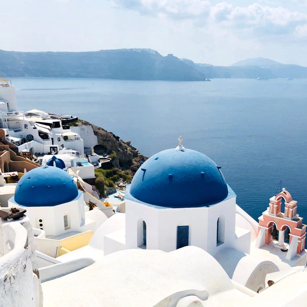 white-washed homes with rounded blue tops overlooking the sea